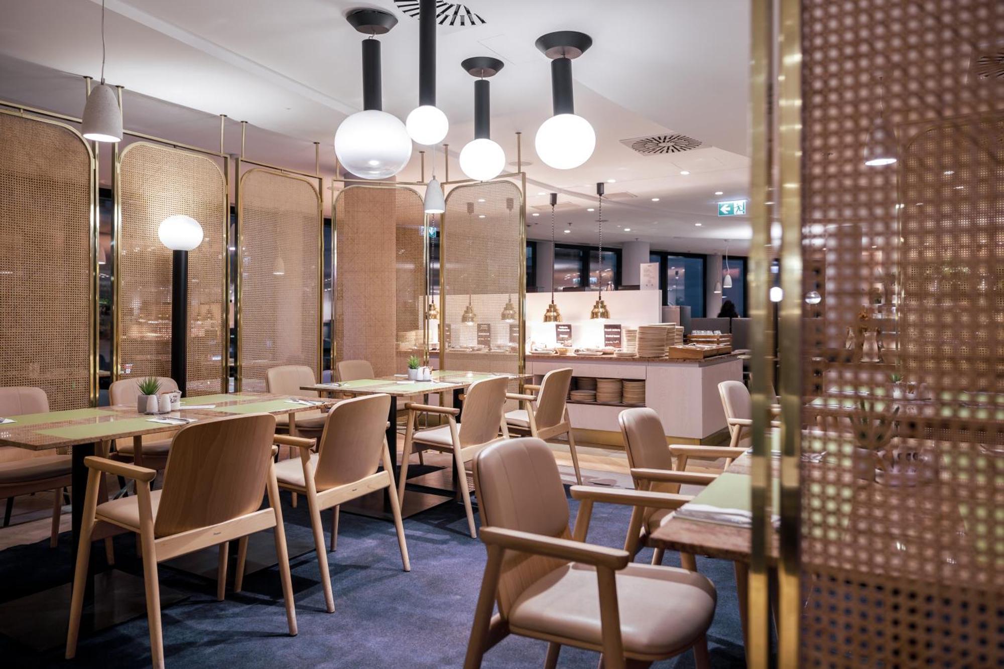 Radisson Blu Resort Świnoujście Екстериор снимка The photo shows a modern restaurant interior. There are wooden tables and chairs arranged neatly. The atmosphere appears warm and inviting, with soft lighting provided by round pendant lamps hanging from the ceiling. Partitions made of woven material