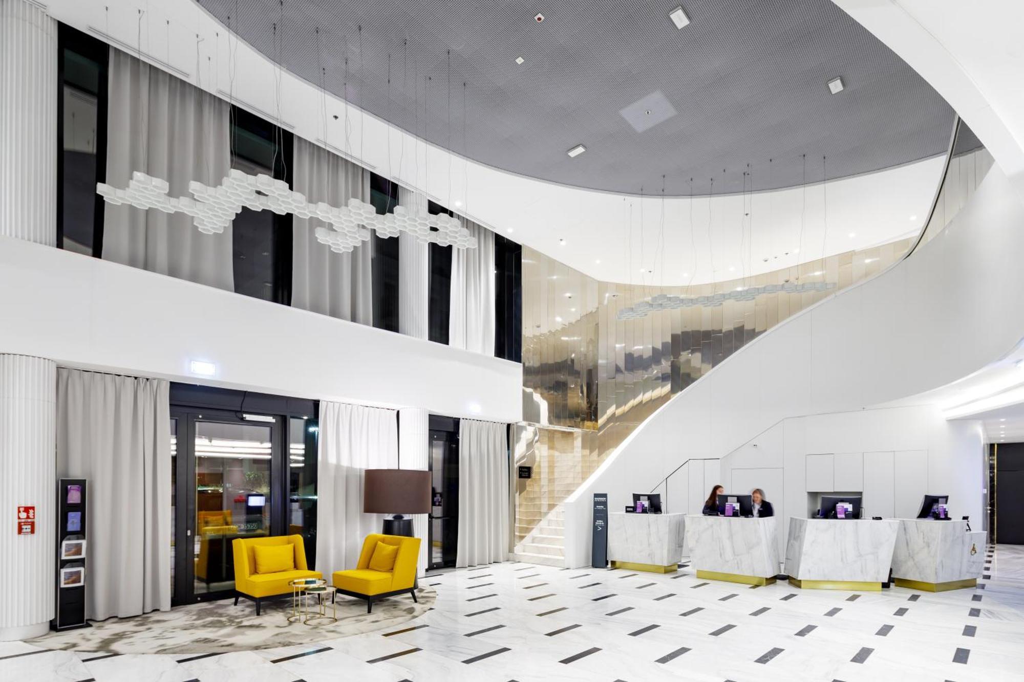 Radisson Blu Resort Świnoujście Екстериор снимка The photo shows a modern interior space, likely a hotel or a lobby area. It features a spacious, open design with high ceilings and a stylish staircase that leads to an upper level. The walls are mostly white, with large windows allowing natural ligh