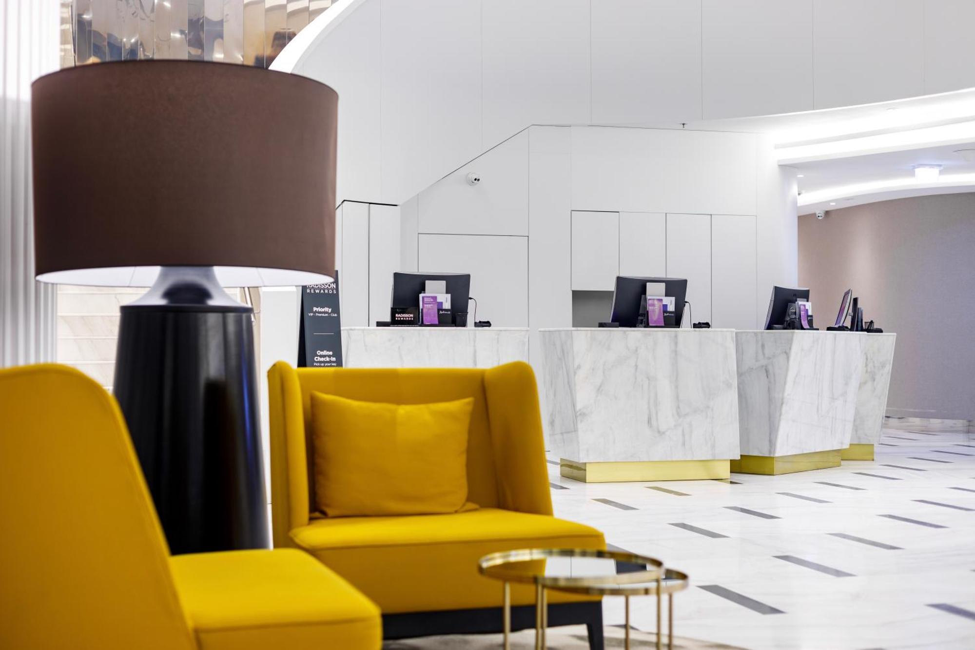 Radisson Blu Resort Świnoujście Екстериор снимка The photo shows a modern reception area, likely of a hotel or a similar establishment. In the foreground, there are two yellow armchairs with soft cushions, situated around a small round table with a minimalist design. Behind the seating area, there 
