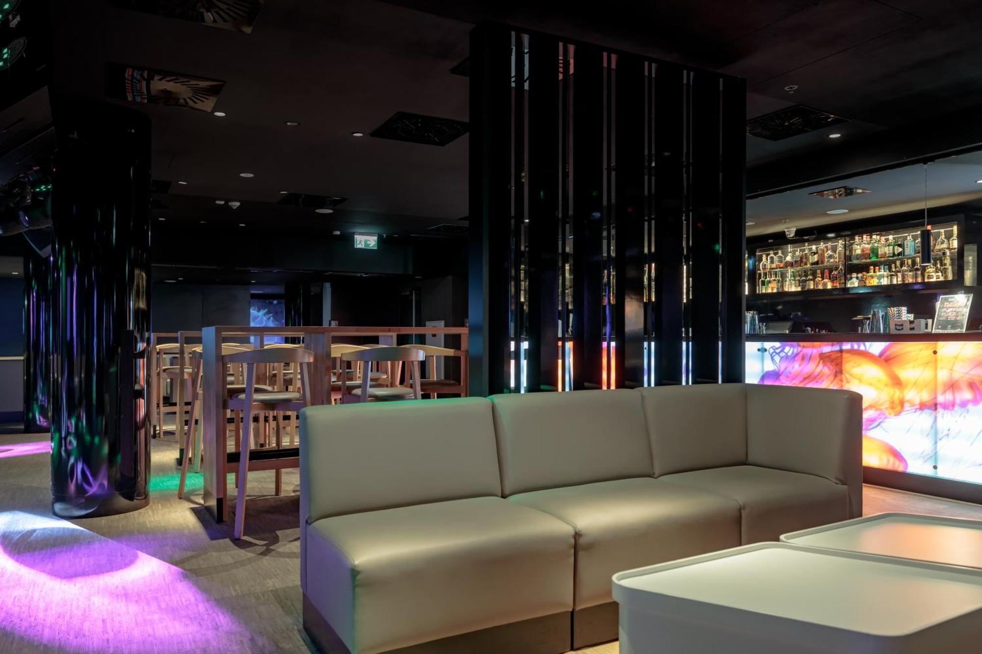 Radisson Blu Resort Świnoujście Екстериор снимка The photo shows the interior of a stylish lounge or bar. The space features a modern design with dark walls and a sleek atmosphere. There is a beige sectional sofa in the foreground, providing a casual seating area. In the background, a bar is visibl
