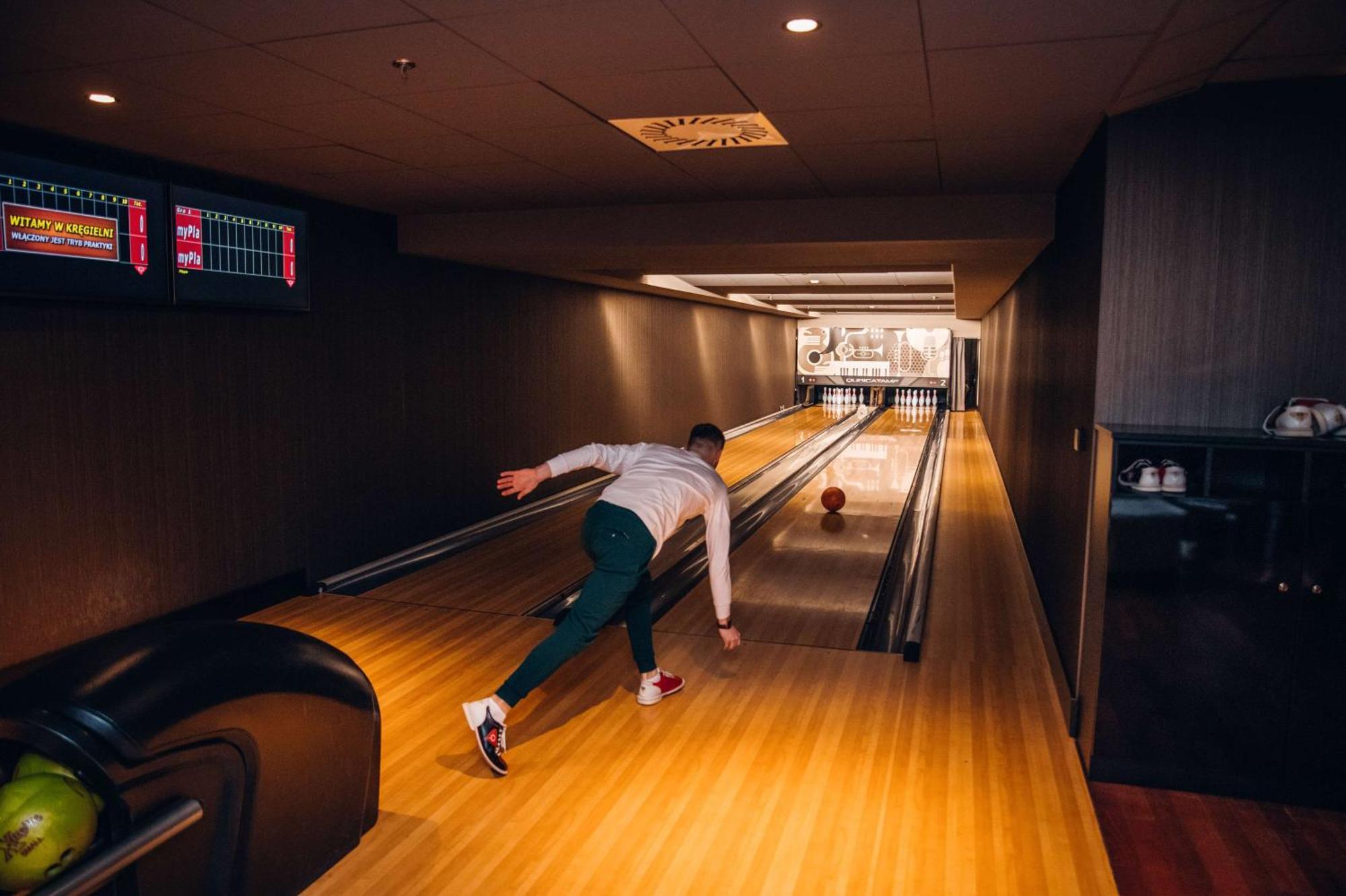 Radisson Blu Resort Świnoujście Екстериор снимка The photo shows a bowling alley. In the foreground, a person is throwing a bowling ball down the lane. They are wearing a white top and green pants, with red and white shoes. The bowling lane is made of polished wood, and at the end of the lane, ther