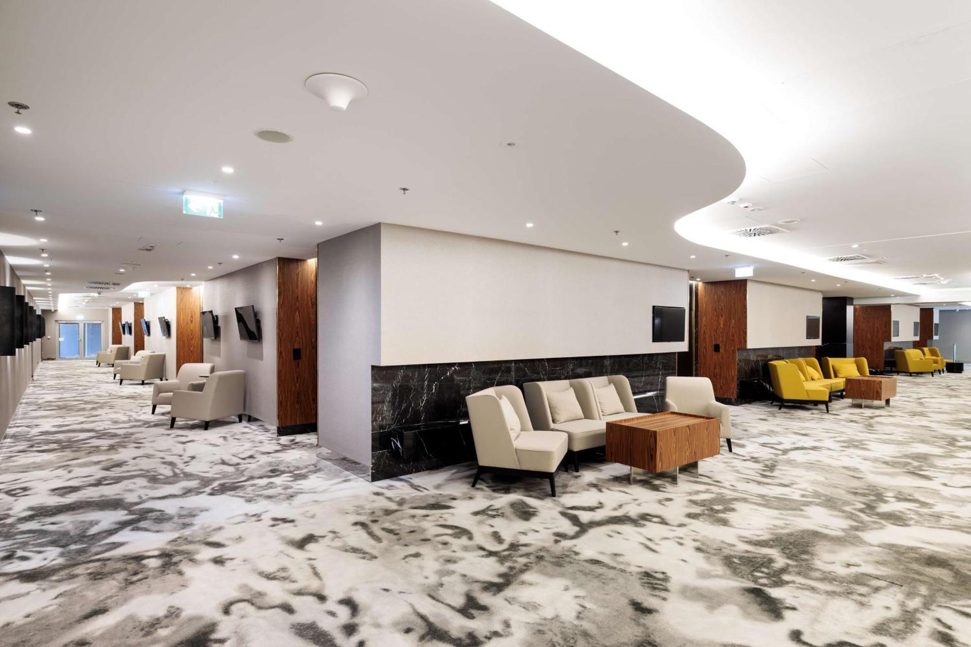 Radisson Blu Resort Świnoujście Екстериор снимка The photo shows a modern interior space, likely a lobby or lounge area. The flooring features a patterned carpet, and the walls are neutral in color, creating a calm ambiance. There are comfortable seating arrangements, including a group of beige cha