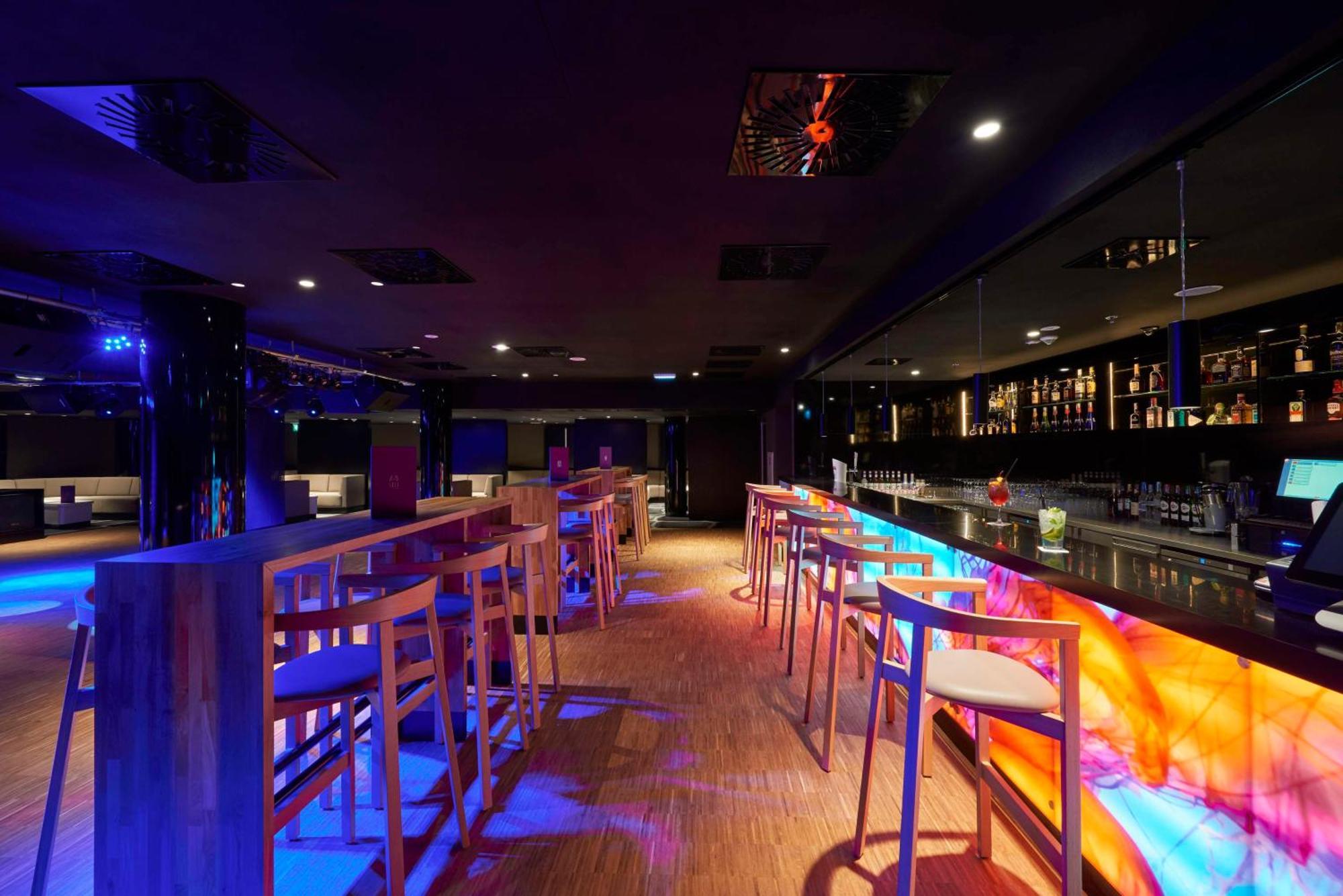 Radisson Blu Resort Świnoujście Екстериор снимка The photo depicts a modern bar interior with a sleek and contemporary design. There are high wooden stools positioned along a bar counter, which features vibrant, colorful lighting underneath. The bar area is dimly lit, creating a nightlife ambiance,