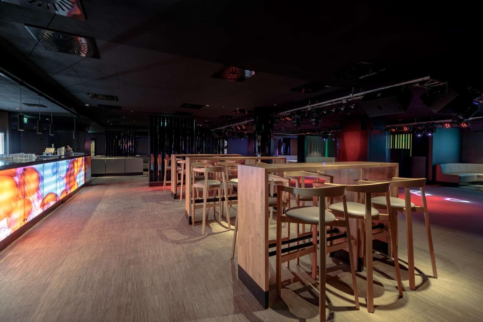 Radisson Blu Resort Świnoujście Екстериор снимка The photo shows an interior space that appears to be a bar or lounge. It features a modern design with a dark color scheme. There are several wooden high-top tables with matching stools arranged in the area. In the background, there is a bar counter,