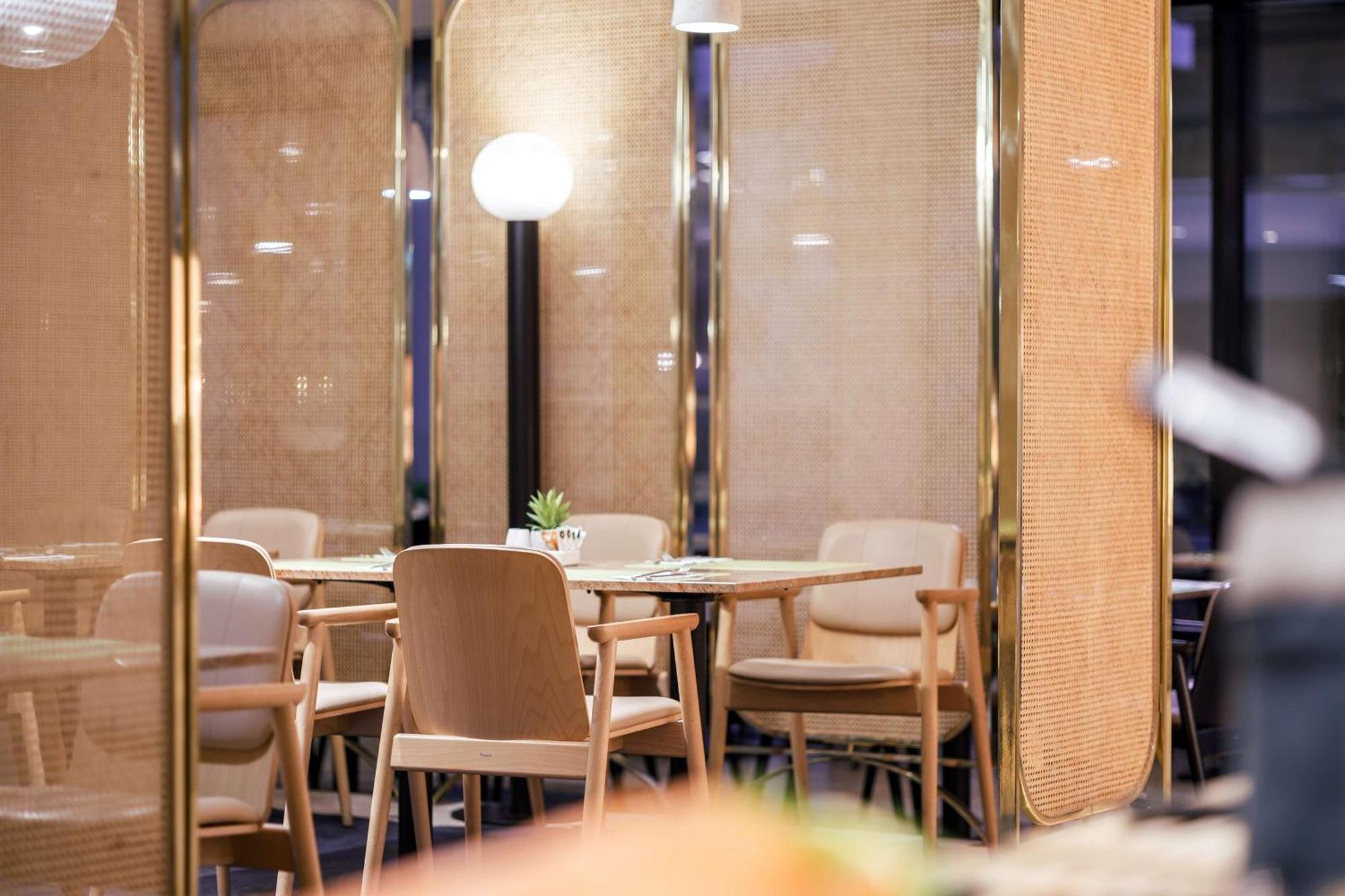 Radisson Blu Resort Świnoujście Екстериор снимка The image shows an interior space, likely part of a restaurant or café. There are several wooden chairs arranged around tables, and the overall decor features soft lighting and warm colors. The walls appear to be partially covered with a woven materi