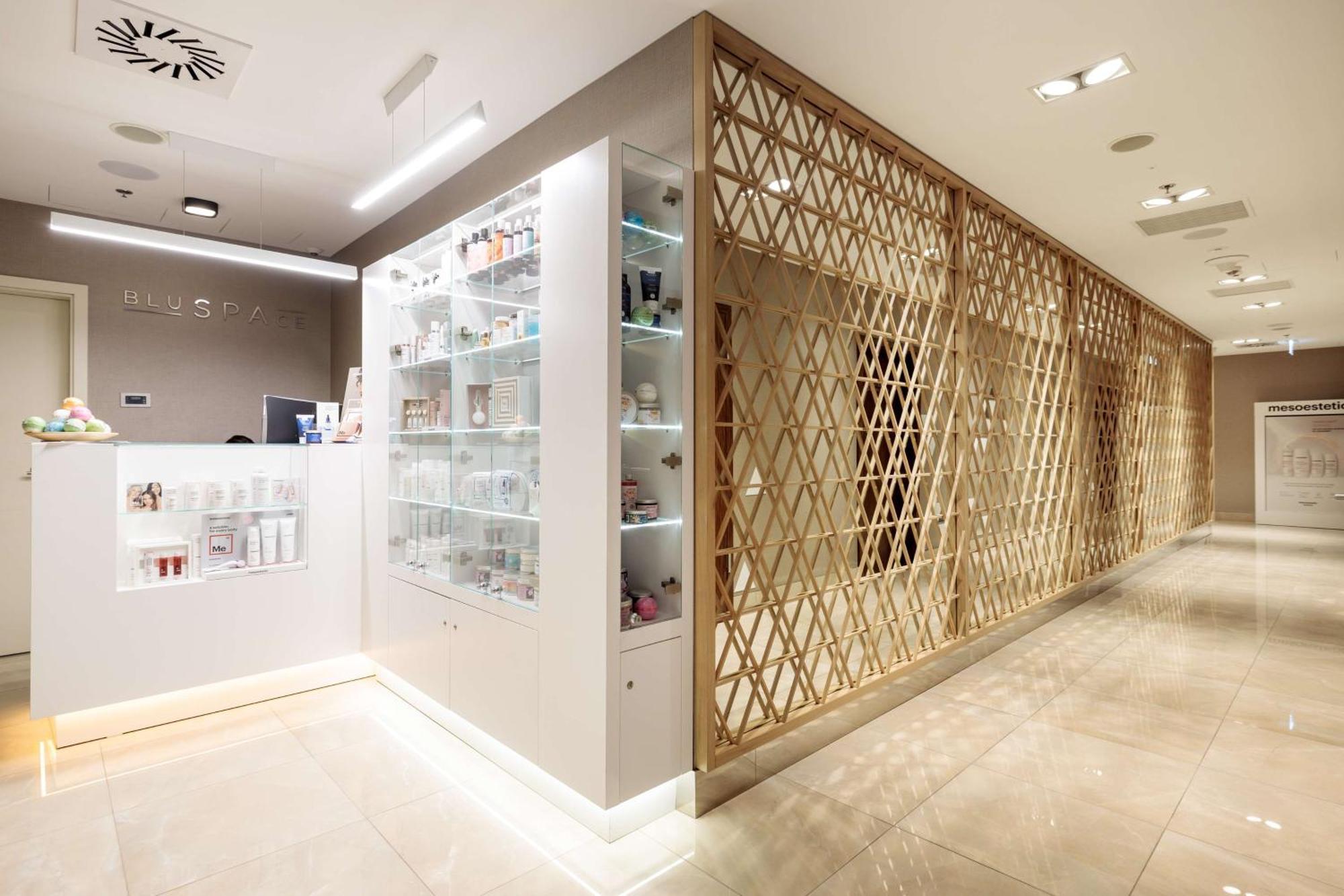 Radisson Blu Resort Świnoujście Екстериор снимка The photo shows a modern interior, likely from a spa or skincare clinic. On the left, there is a reception area with a sleek white counter and an illuminated display showcasing various skincare products. The wall behind the reception features a glass