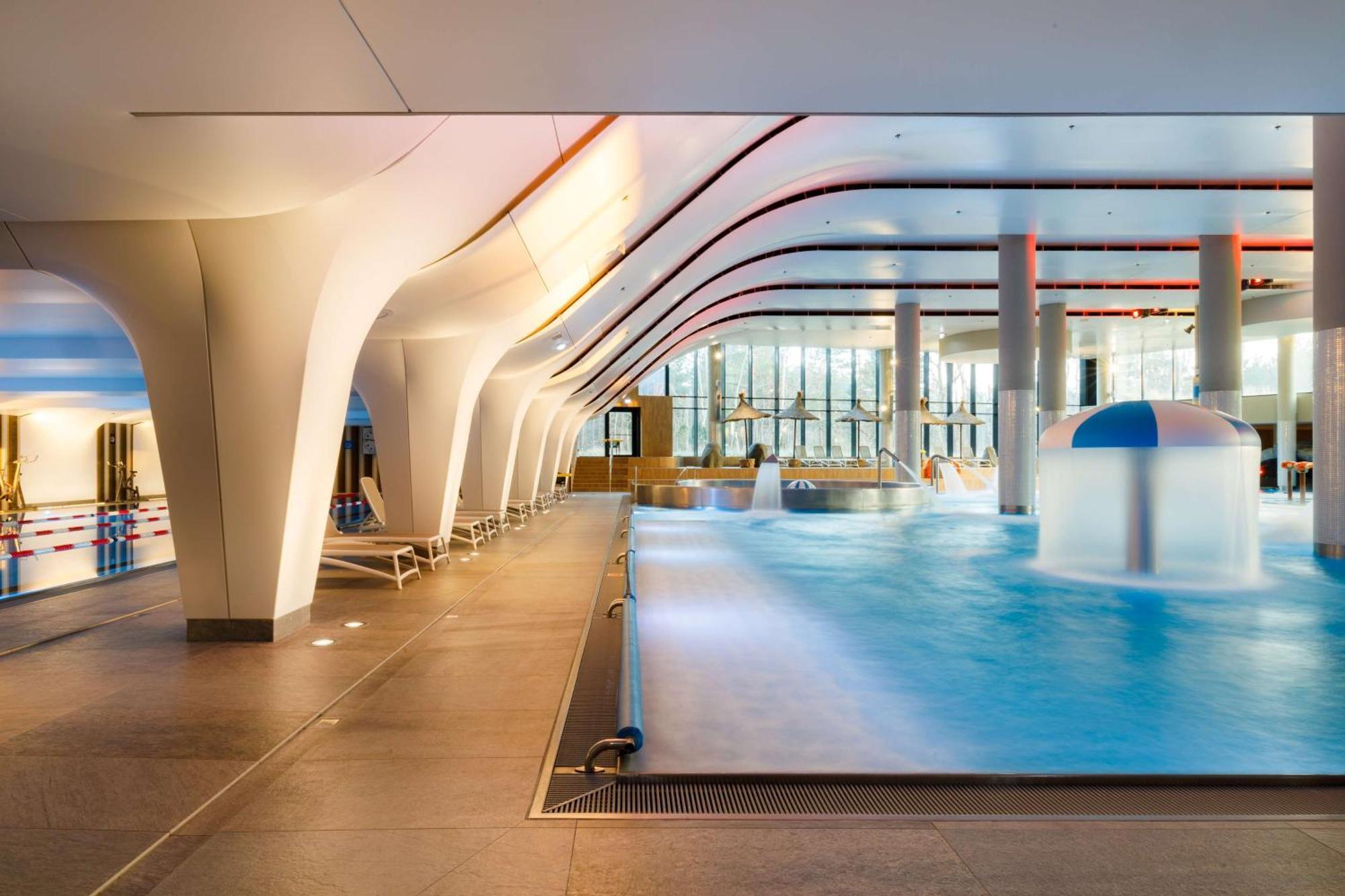 Radisson Blu Resort Świnoujście Екстериор снимка The photo shows an indoor swimming pool area with a modern architectural design. The space features large windows allowing natural light to enter, and the interior has smooth, flowing lines in the ceiling and columns. The pool has a light blue water 